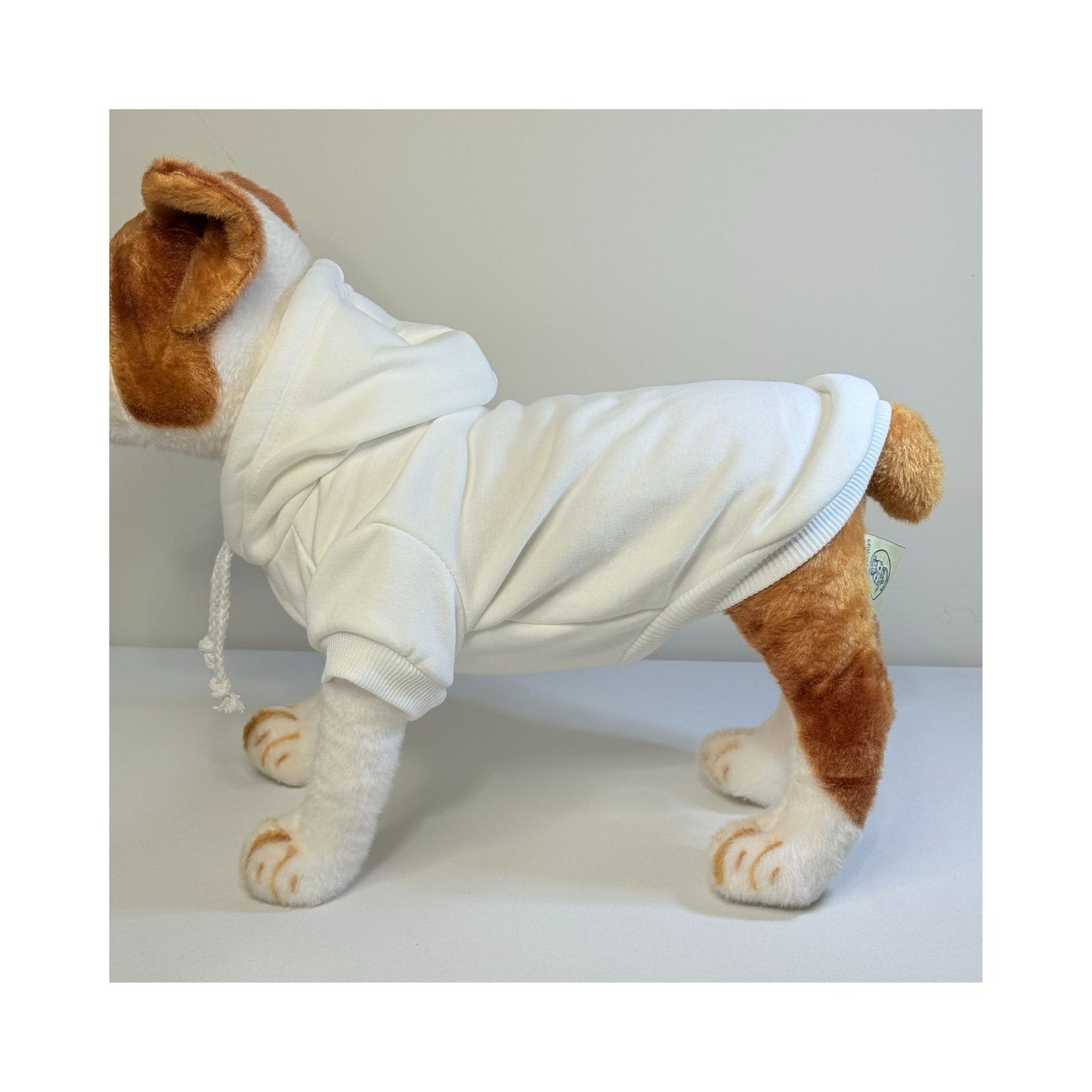 Side view of a stuffed dog model wearing a cream pet hoodie, showing the fit along the back, sleeves, and ribbed hem.