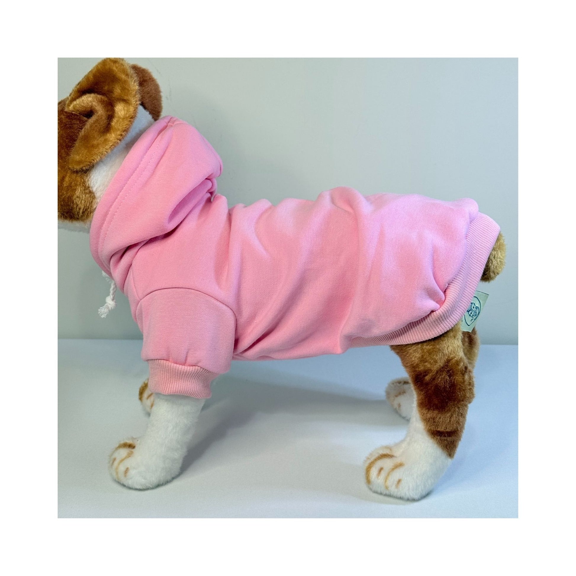 Side view of a plush dog mannequin wearing a light pink fleece-lined pet hoodie with ribbed trim and hood detail